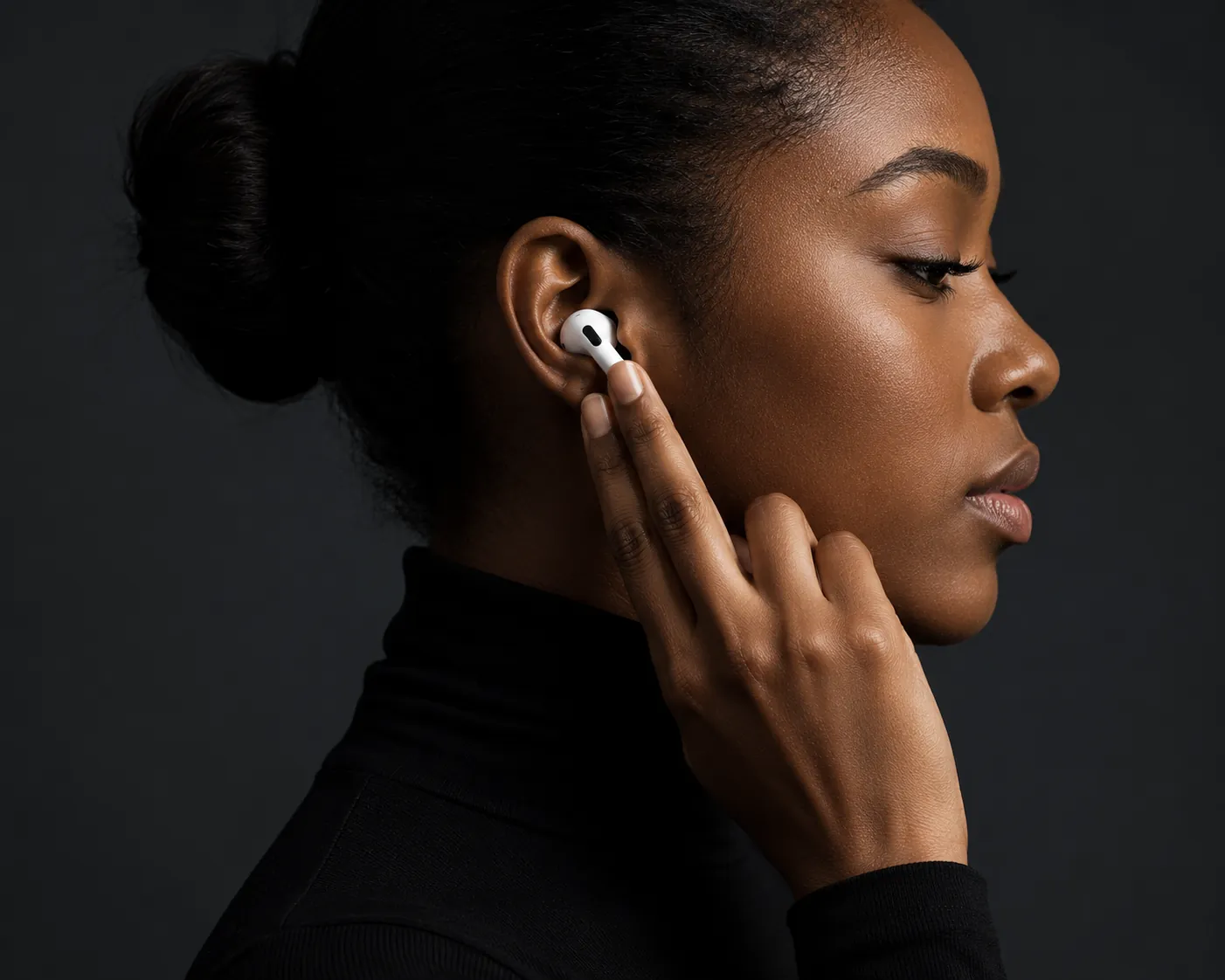 Woman wearing AirPods, dark studio portrait