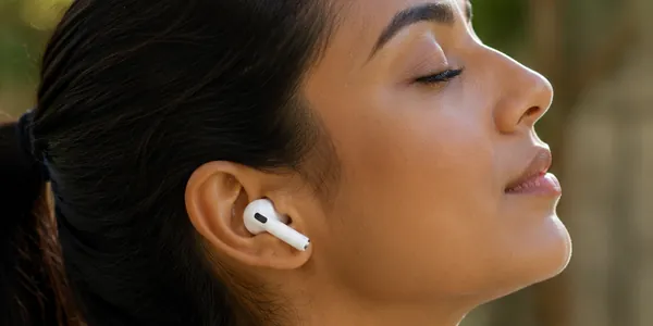 Woman wearing AirPods outdoors in soft light